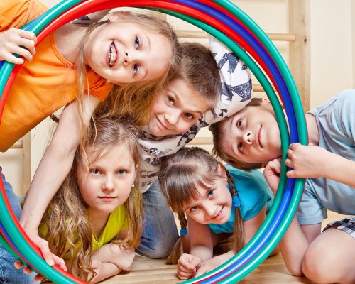 Portrait of laughing children looking through hula hoops